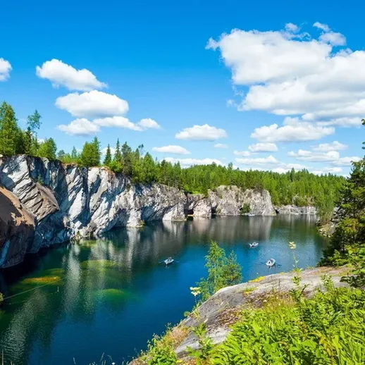 Красивый каменистый карьер с голубым озером и зелеными лесами под ясным небом на северо-западе России