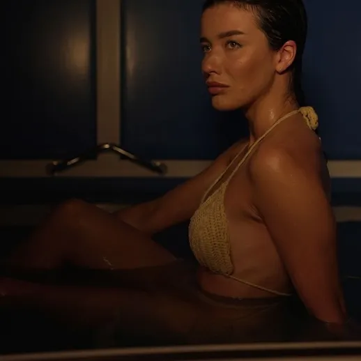 Молодая женщина отдыхает в ванне с теплой водой в темном помещении в вечернее время