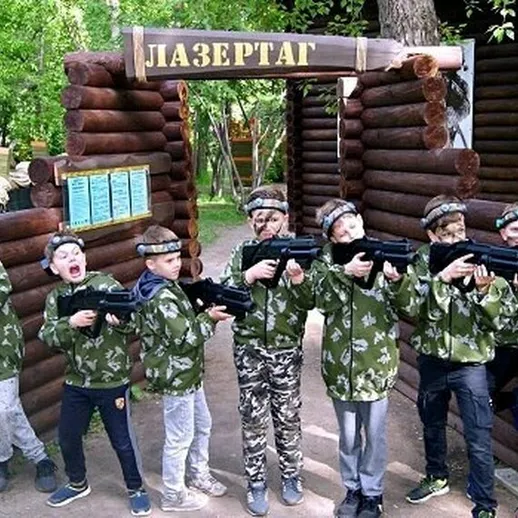 Дети в камуфляже с лазерными винтовками на игровой площадке летом