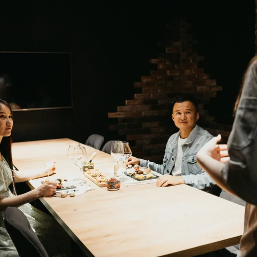 Уютный вечер с друзьями за столом в темноте, обсуждая планы на будущее и наслаждаясь вкусной едой в ресторане