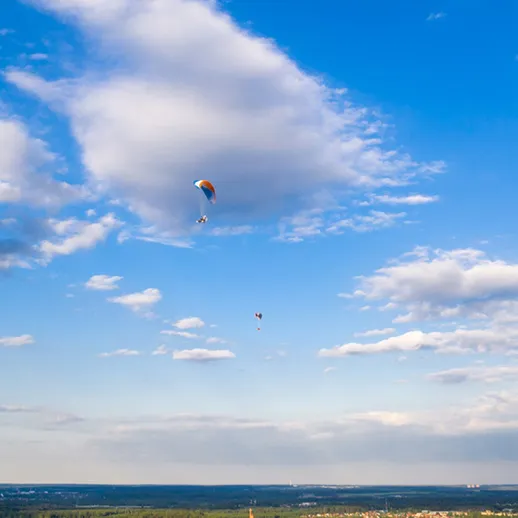 Парапланеристы в небе над живописным пейзажем в ясный день