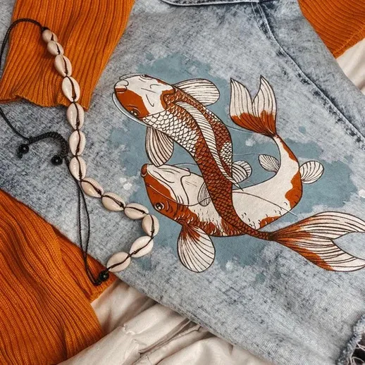 Денимовая куртка с рисунком карпов на фоне оранжевого свитера и нейтрального полотна в уютной обстановке