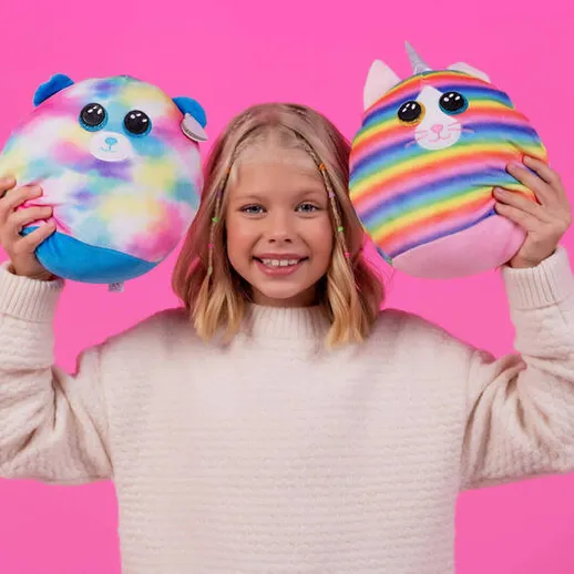 Девочка держит игрушки в руках на фоне яркой стены