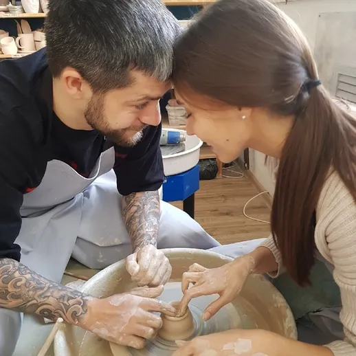 Пара создает керамическое произведение на гончарном круге в уютной мастерской