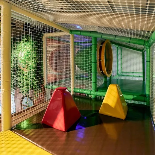 Игровая зона для детей с теневой сеткой и яркими препятствиями в развлекательном центре