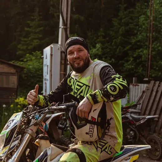 Мотокроссмен на мотоцикле готовится к заезду на трассе в лесу в светлое время суток