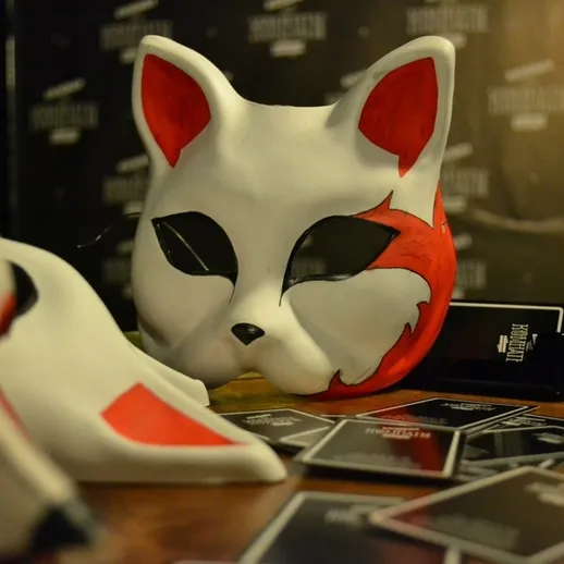 Маска белого лиса на столе среди карт в уютном кафе на вечеринке в стиле косплея