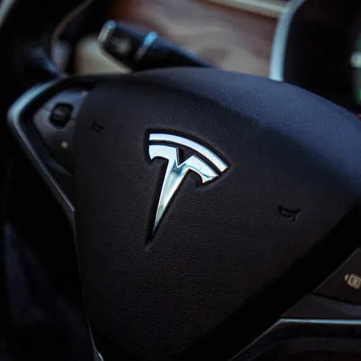 Удобный руль Tesla с логотипом на фоне интерьера электромобиля на парковке