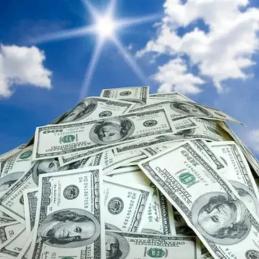 Куча долларов на фоне голубого неба и яркого солнца в теплый день