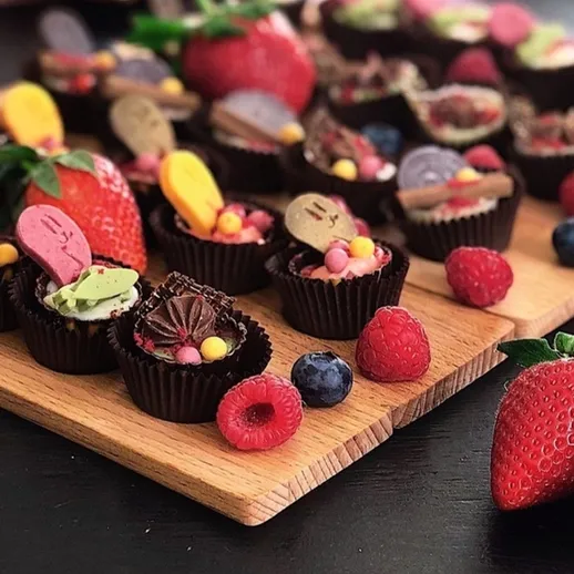 Набор сладких десертов на деревянной доске, украшенных ягодами и конфетами для наслаждения в праздничный вечер