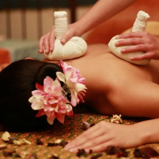 Расслабляющий массаж с горячими травяными мешочками в спа-салоне на фоне тропической природы