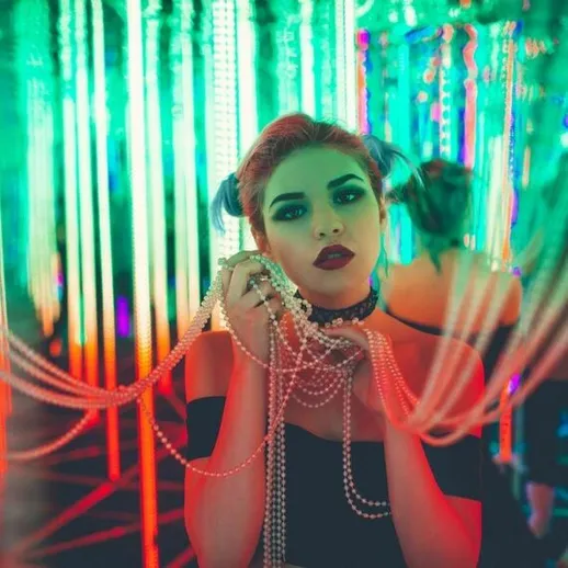 Девушка с жемчужными украшениями на фоне ярких неоновых огней в ночном клубе