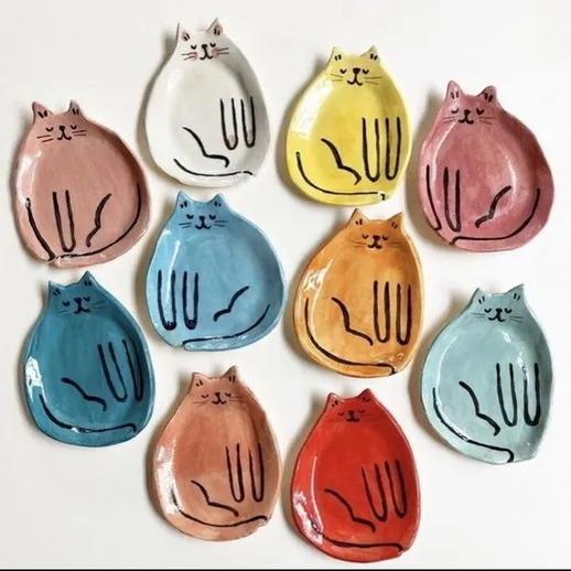 Керамические тарелки с изображением котов разных цветов, выставленные на белом фоне для художественной демонстрации