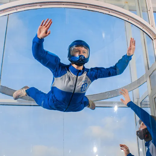 Ветропорта на обучении: человек в свободном падении в аэродинамической трубе на фоне ясного неба