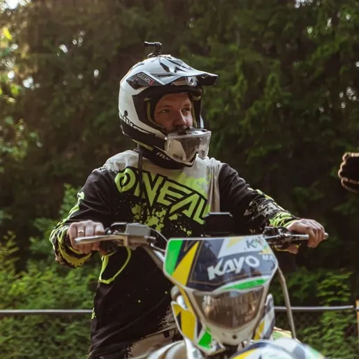 Мотоциклист на трассе для кросса наслаждается поездкой в лесу солнечным днем