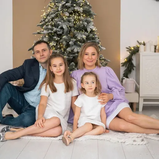 Счастливая семья на уютном семейном празднике возле рождественской ели в светлом интерьере