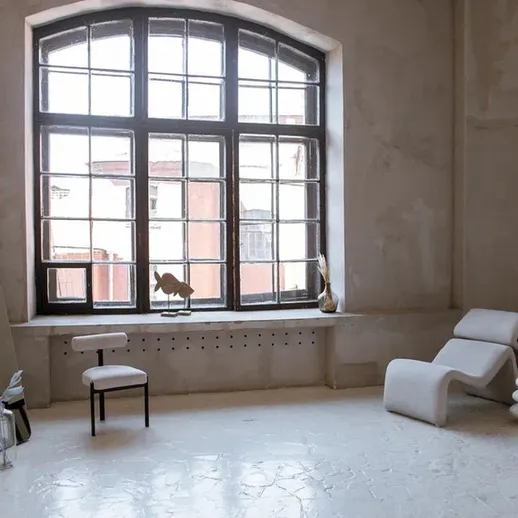 Просторное помещение с большими окнами и минималистичной мебелью в светлых тонах