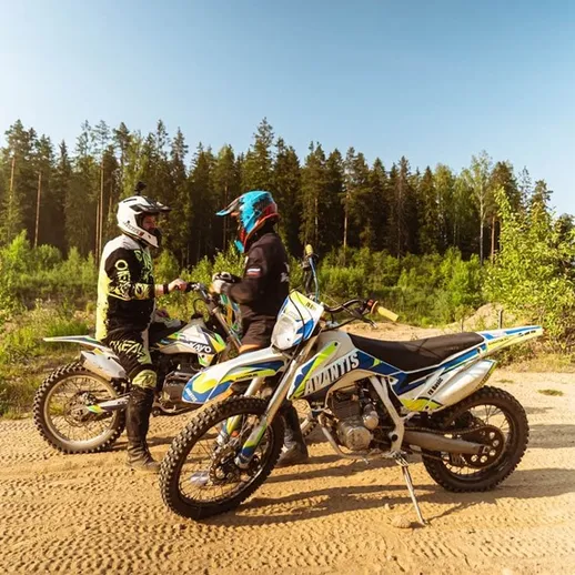 Два мотоциклиста обсуждают маршрут в лесной местности на разбитом грунте в летний день