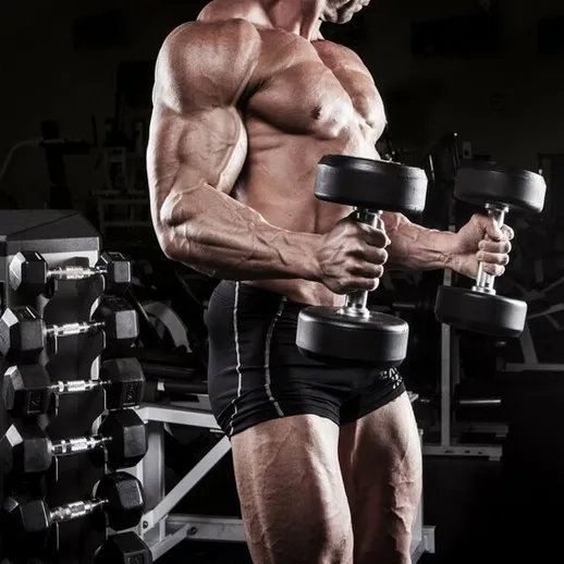 Сильный атлет lifting гантели в тренажерном зале в вечернее время