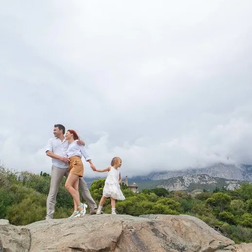 Счастливая семья на прогулке по скалам в окружении зелени и облаков в Крыму