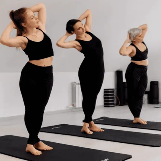 Три женщины занимаются йогой в спортзале в утренние часы на ковриках для занятий