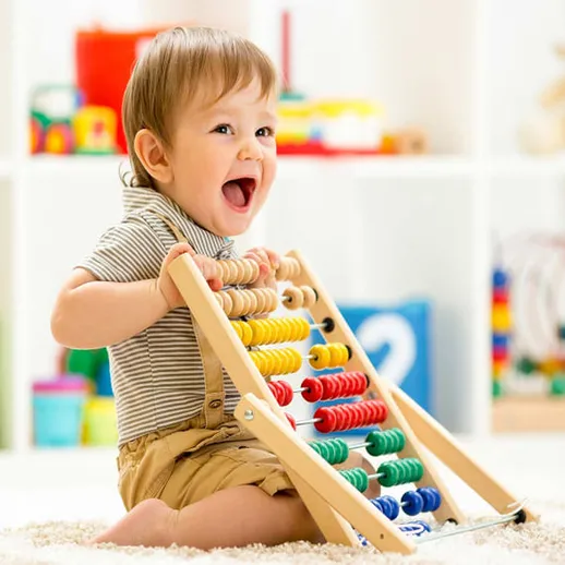 Маленький ребёнок играет с игрушечным счётчиком и радуется в уютной комнате в дневное время