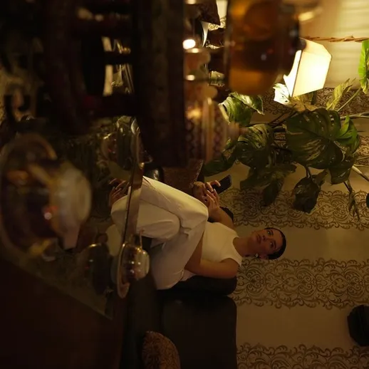 Уютная комната с уютным интерьером и женщиной в белом, отдыхающей на диване вечером