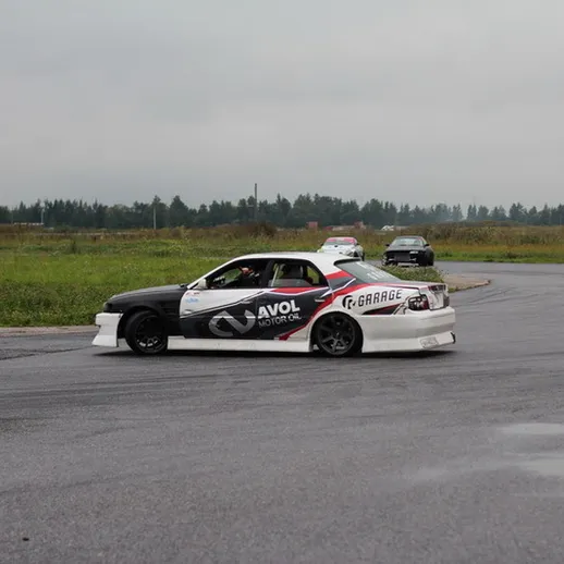 Дрифт-кар выполняет маневр на автомобильной трассе в дождливую погоду