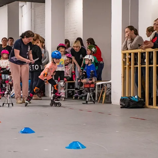 Дети учатся кататься на роликах в спортивном зале на тренировке