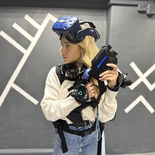 Виртуальная реальность: девушка в VR шлеме держит контроллеры для игры на арене