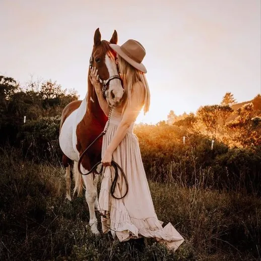 Женщина обнимает лошадь на закате в пасторальном пейзаже