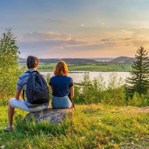 Влюбленная пара на берегу реки наслаждается закатом в живописной местности