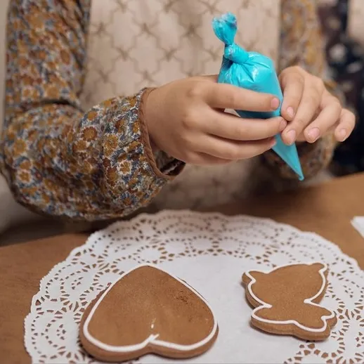 Изготовление печенья в форме сердца и бабочки в уютной кухне в процессе украшения в зимний вечер