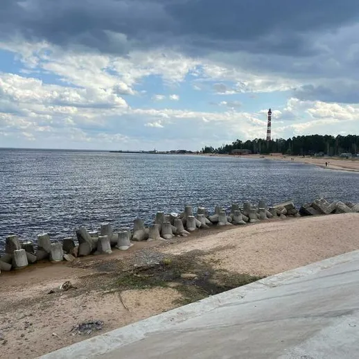 Уютный берег реки в солнечный день с облаками, вид на маяк и заповедное побережье