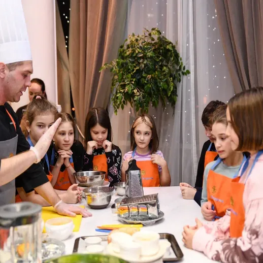 Дети учатся готовить в кулинарном классе под руководством шеф-повара в уютном заведении