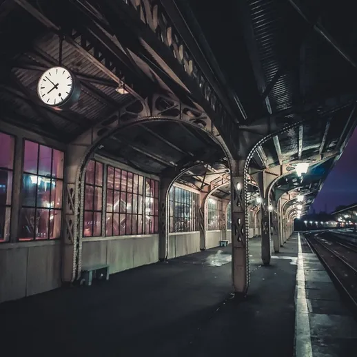 Старый вокзал с часами, пустая платформа и приглушённый свет в вечернее время