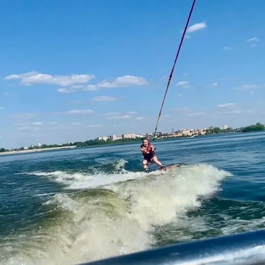 Вейкбордист выполняет трюки на воде в солнечный день рядом с городом