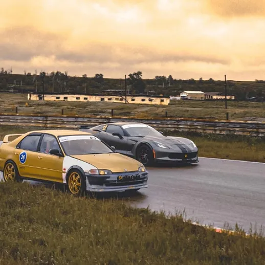 Автомобили на гоночной трассе под желтым небом в преддверии заката