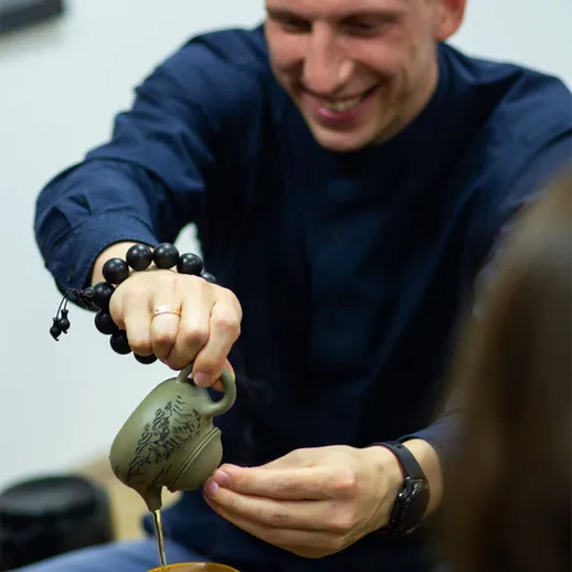 Мужчина наливает чай из глиняного чайника во время чайной церемонии в уютной комнате