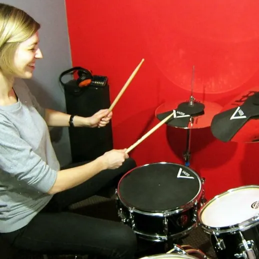 Женщина играет на ударных инструментах в студии звукозаписи во время репетиции