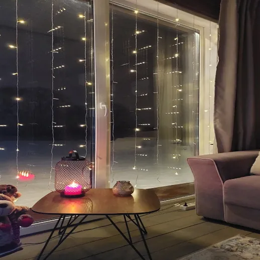 Уютная комната с ёлочными огнями и мягким светом свечи в зимний вечер