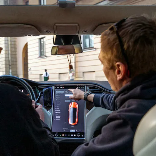 Мужчины обсуждают функции автомобиля в салоне на фоне городской улицы