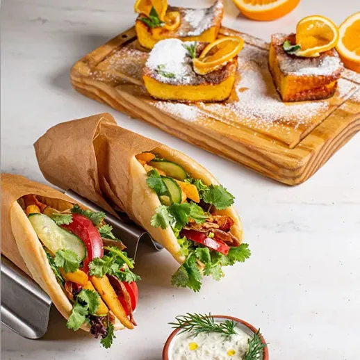 Вкусные тако с овощами и мясом на фоне десерта с апельсинами в кафе