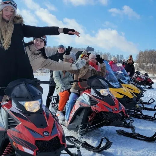 Группа людей на снегоходах наслаждается зимними развлечениями на заснеженной местности