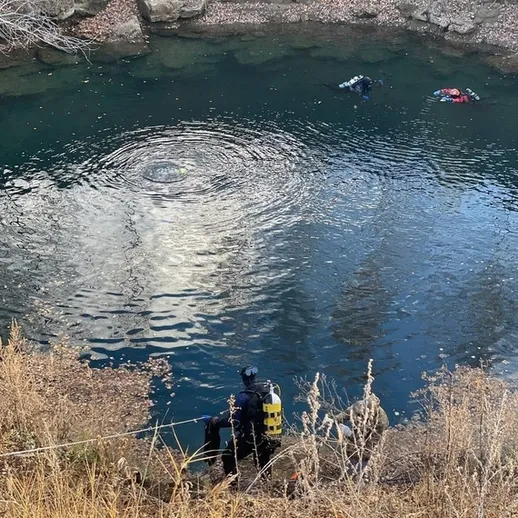 Специалист по водолазным работам проводит обследование подводной местности в реке осенью