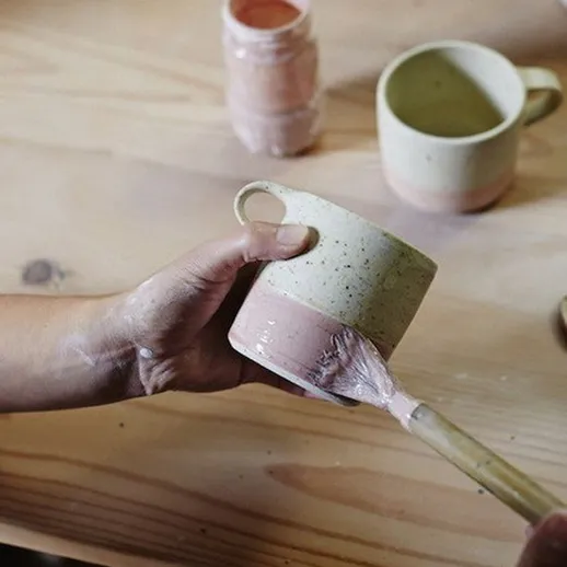 Изготовление керамической кружки на деревянном столе в мастерской в течение дня