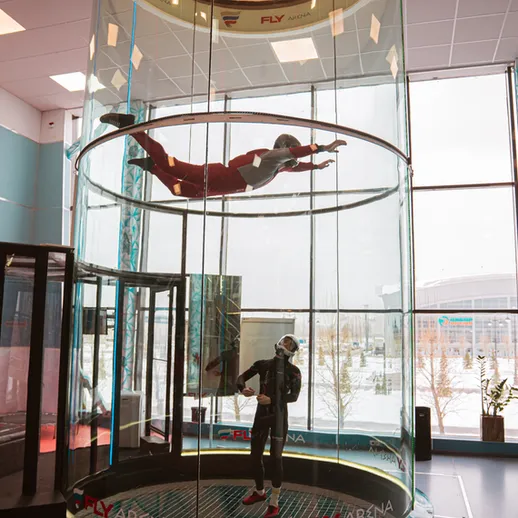 Парашютист в вертикальном ветровом туннеле в спортивном комплексе зимой