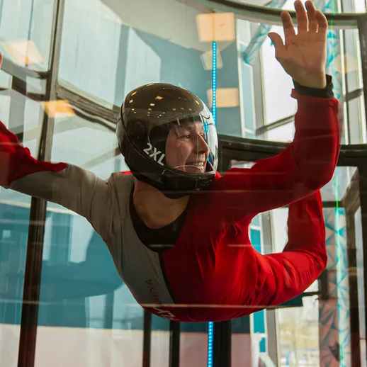 Спортсмен в аэродинамической трубе демонстрирует навыки фри-флайнинг на соревнованиях в закрытом помещении