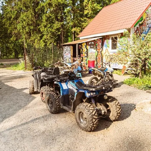 Наездники на квадроциклах возле уютной базы отдыха в лесу в летний день