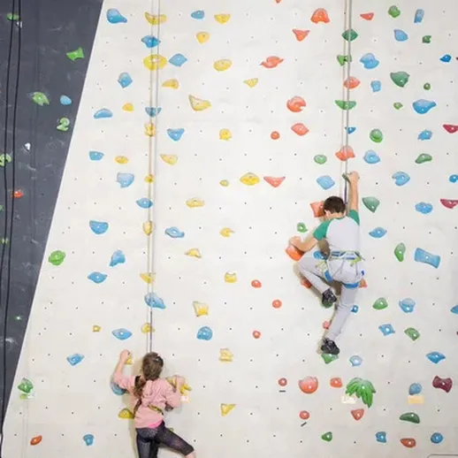 Молодые альпинисты воплощают смелость в тренировке на скалодроме